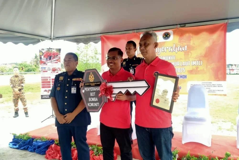 Khairul Anuar (kiri) bersama Mohamad Yusri (tengah) menyempurnakan gimik penyampaian replika kunci enjin bot dalam Majlis Penyerahan Bot Bomba Komuniti Sempena Persediaan MTL Zon 4 JBPM Perak 2025 di Taman Tasek Temoh, Tapah pada Ahad.