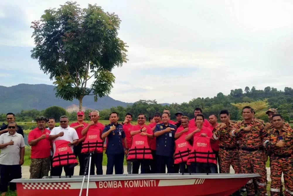 Khairul Anuar (enam dari kanan) dan Mohamad Yusri (enam dari kiri) bersama pasukan bomba komuniti serta anggota JBPM selepas Majlis Penyerahan Bot Bomba Komuniti Sempena Persediaan MTL Zon 4 JBPM Perak 2025 di Taman Tasek Temoh, Tapah pada Ahad.