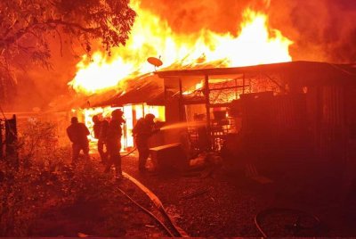 Anggota bomba berusaha memadamkan kebakaran yang memusnahkan enam buah rumah di Jalan Mak Intan, Kampung Terengganu, Teluk Intan tengah malam tadi.