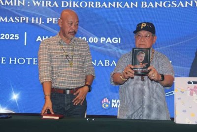Pandikar (kanan) menunjukkan buku mengenainya yang ditulis oleh Dr Maspi di Kota Kinabalu pada Ahad.