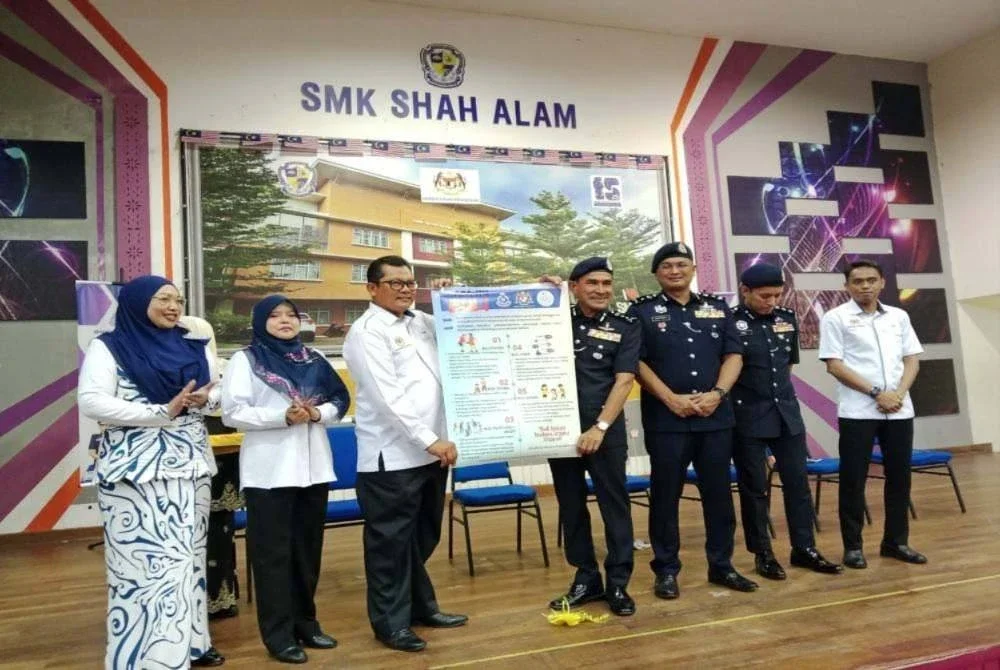 Mohd Zaini menyerahkan poster Kempen Anti Buli dalamperhimpunan pagi di Sekolah Menengah Kebangsaan (SMK) Shah Alam di sini pada Isnin.