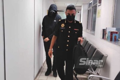 Tertuduh (belakang) dihadapkan ke Mahkamah Sesyen Kuala Terengganu atas 79 pertuduhan menerima rasuah berjumlah RM488,050 antara 2018 hingga 2022.