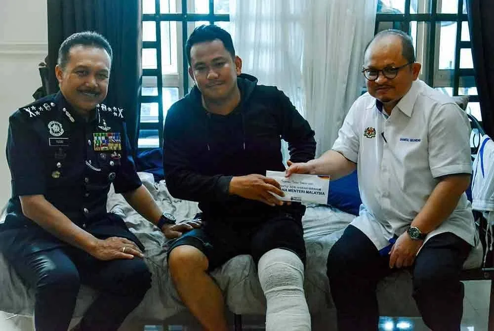 Pengarah Jabatan Siasatan dan Penguatkuasaan Trafik (JSPT) Bukit Aman, Datuk Seri Mohd Yusri Hassan (kiri) menyampaikan bantuan kepada Koperal Kamarul Suari (tengah) yang cedera dalam kemalangan ketika mengiringi delegasi antarabangsa sempena Sidang Kemuncak ASEAN ke-47 baru-baru ini. Turut hadir Setiausaha Politik Kanan Perdana Menteri, Datuk Seri Shamsul Iskandar Mohd Akin (kanan). Foto Bernama