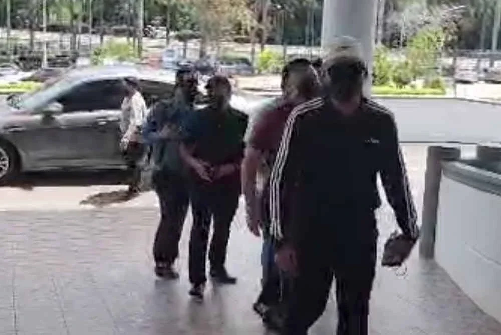 Mohamad Fazil (bertopi) ketika tiba di pekarangan Mahkamah Majistret Melaka pada Selasa bagi perbicaraan mencederakan seorang pengurus syarikat insurans tahun lalu.