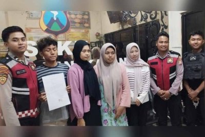 Suspek (dua dari kiri) menandatangani surat persetujuan bahawa dia tidak akan mengulangi perbuatannya. Foto Agensi