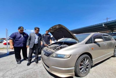 Mohammad Yusoff (tengah) menunjukkan kenderaan sitaan yang berjaya dilelong menerusi Majlis Lelongan Awam pada Selasa.