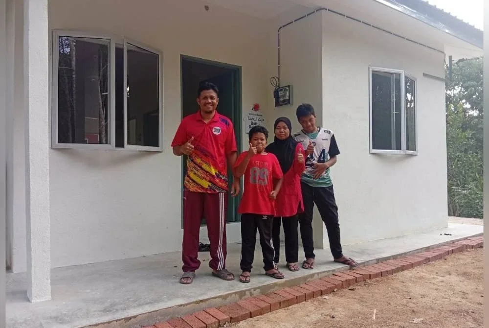 Shahadan (kiri) bersama isteri dan dua anak gembira dapat memiliki kediaman sendiri yang dibina menerusi program Baitul Rahmah.