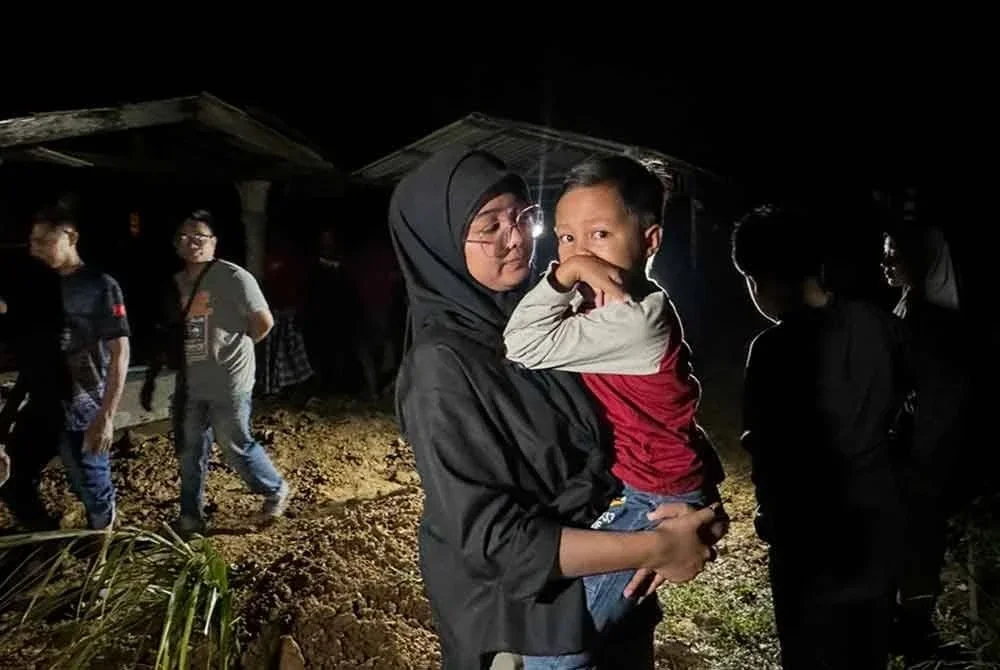 Farisha (kiri) menenangkan Nur Musyrif Syafi yang menangis sejurus jenazah bapa angkat mereka selamat disemadikan di Tanah Perkuburan Islam Pangkal Kuang 2, Kampung Dendang, Ketereh, Kota Bharu pada awal pagi Jumaat.