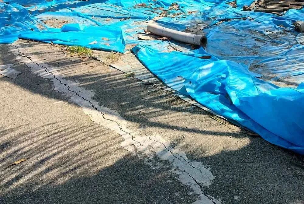 Kesan retakan pada jalan yang berada berhampiran kawasan ban pencegah banjir yang pecah di Perumahan Bukit Rangin Perdana 2.