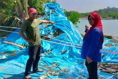 Yusnizar dan Khairul Azlan menunjukkan kawasan ban pencegah banjir di kawasan Perumahan Bukit Rangin Perdana 2, Kuantan yang pecah sejak April lalu dan belum dibaiki.