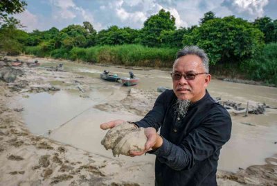 Pengerusi Jaringan Perikanan Nelayan Darat Masyarakat Orang Asli Parlimen Tenggara merangkap Pengerusi JPKKOA Kampung Orang Asli Sayong Pinang, Jasni Amat, menunjukkan lumpur yang dipercayai menjadi punca pencemaran sungai. Foto Bernama