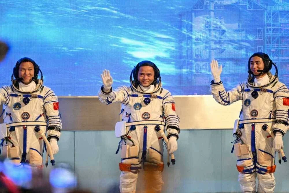 Angkasawan misi angkasa China Shenzhou-21, Zhang Hongzhang (kiri), Komander Zhang Lu (tengah) dan Wu Fei (kanan), melambaikan tangan semasa upacara pelepasan sebelum berangkat menaiki bas menuju ke kapal angkasa Shenzhou-21 di Pusat Pelancaran Satelit Jiuquan, Gurun Gobi, barat laut China. -AFP