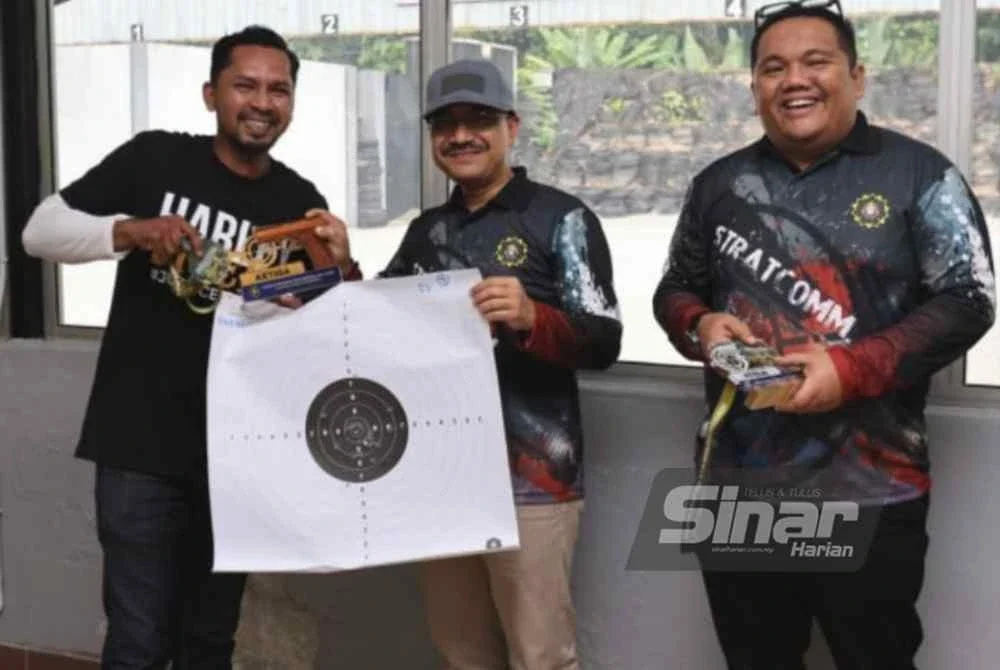 Saiful Ezral (tengah) menyampaikan hadiah kepada petugas media yang terlibat dalam Program Menembak SPRM Bersama Media di Lapang Sasar Maktab Penjara Kajang pada Sabtu.