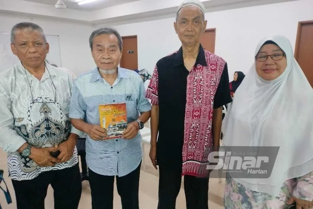 Abdul Rahim (dua dari kanan) dan Kamdi (dua dari kiri) menunjukkan buku sejarah Kampung Melayu Majidee.