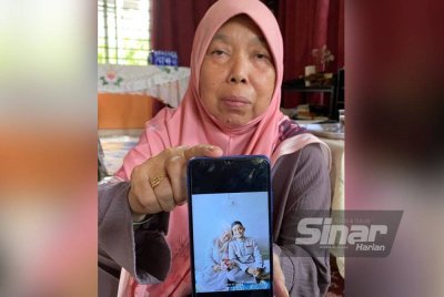 Zaiton menunjukkan gambar anak keempat daripada enam beradik semasa ditemui di rumahnya di Kampung Kepas Apam, Pasir Mas pada Ahad. Foto: SINAR HARIAN/HAZELEN LIANA KAMARUDIN