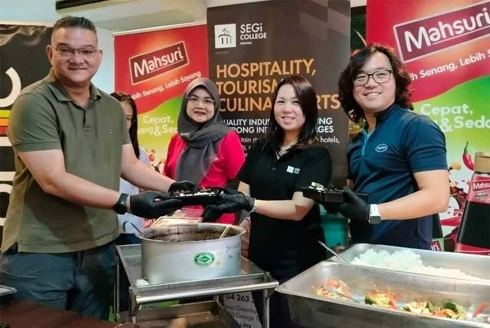 Mohd Jazri (kiri) dan Mi-Chelle (dua dari kanan) membantu menyiapkan bungkusan makanan untuk diedarkan kepada empat rumah kebajikan di sekitar George Town pada Ahad.