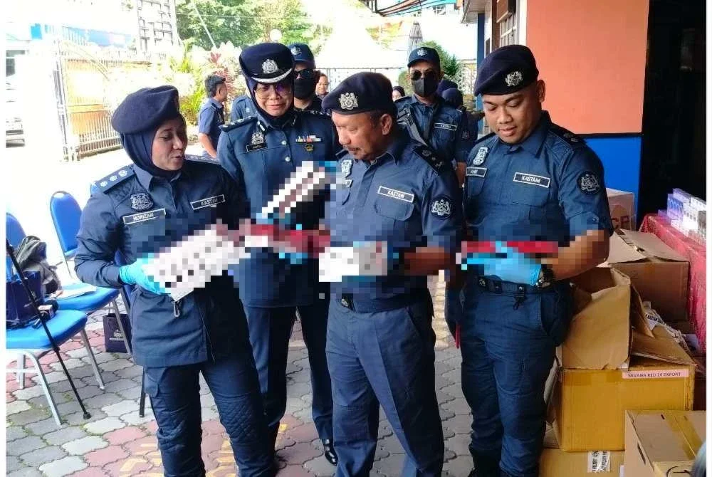 Mohd Asri (tengah) memeriksa rokok putih tidak bercukai pelbagai jenama yang dirampas hasil serbuan ke atas sebuah rumah di Indera Mahkota 21 Ahad lalu