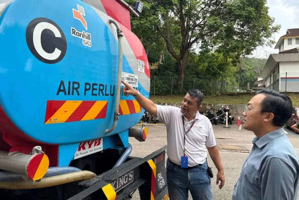 Bor Yang (kanan) diberikan taklimat mengenai bekalan air bersih disalurkan kepada pelajar UTM yang terjejas.