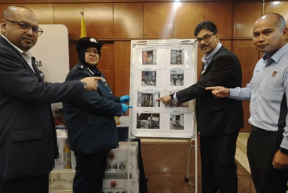 Wan Norizan (dua dari kiri) menunjukkan kontena yang ditahan mengandungi besi dan skrap.