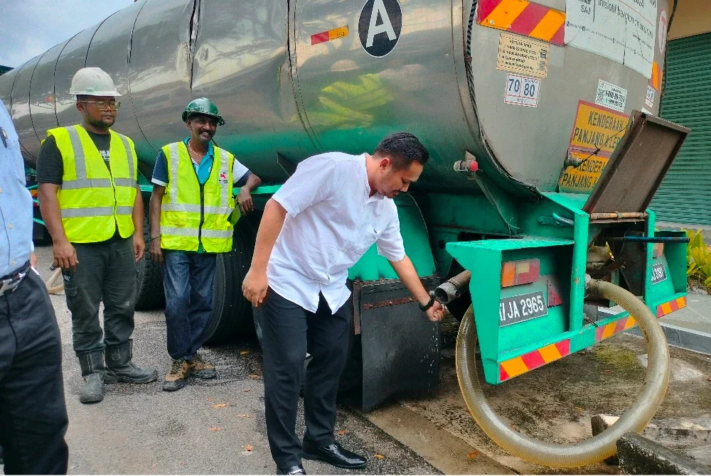 Mohamad Fazli (kanan) ketika meninjau agihan air daripada lori tangki di Taman Impian Emas, Skudai pada Rabu.