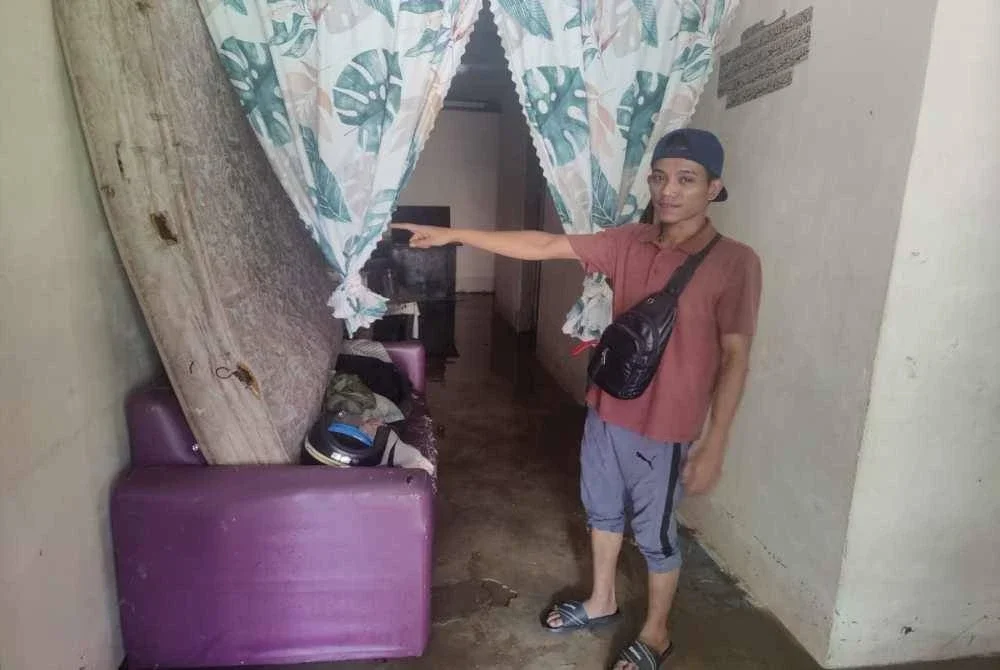 Mohd Azhar menunjukkan kesan banjir yang melanda kediamannya di Kampung Sentosa, pada Khamis.