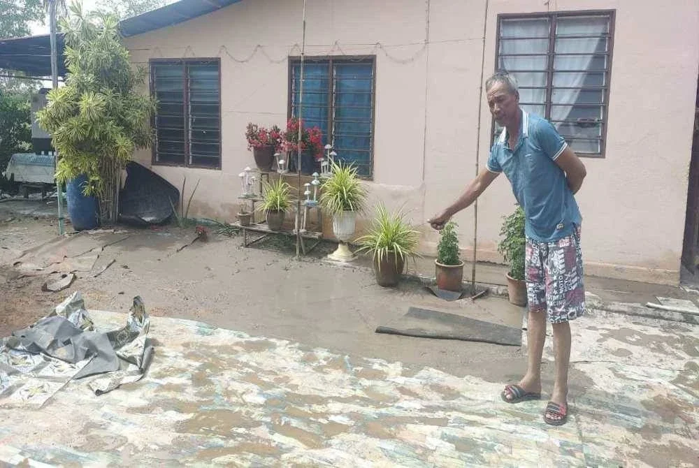 Mohd Solihin menunjukkan barangan yang sempat dialih selepas rumah mereka digenangi air pada Khamis.