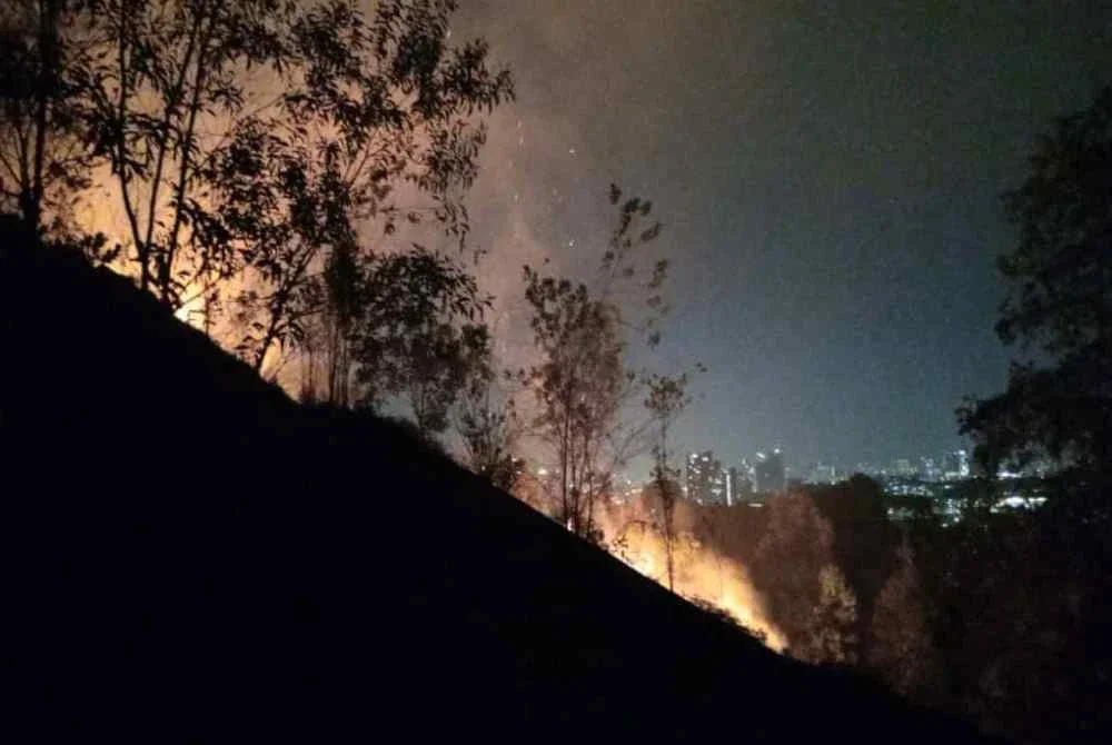 Anggota bomba sedang memadamkan kebakaran hutan di bukit Taman Seri Timah, pada Khamis.