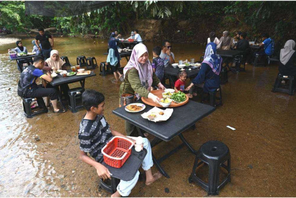 Antara pengunjung yang menjamu selera sambil mencari ketenangan di aliran air sungai di Warung Sungai Berakir, Kampung Tapah, Hulu Terengganu.