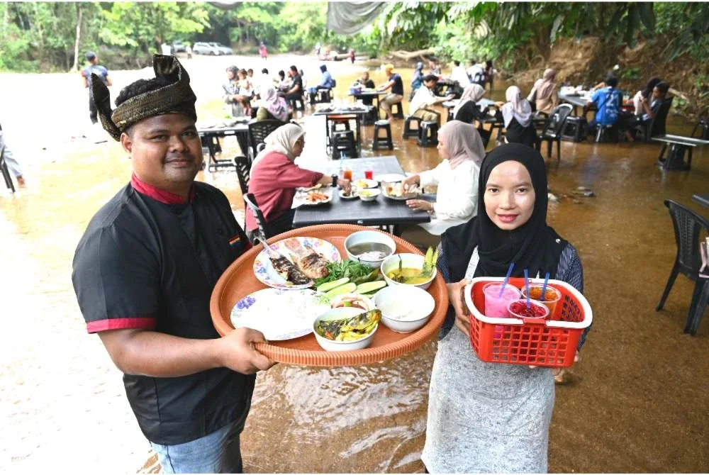 Nasiruddin (kiri) dan Nur Jannah menunjukkan antara hidangan yang disediakan di Warung Sungai Berakir di Kampung Tapah, Hulu Terengganu.