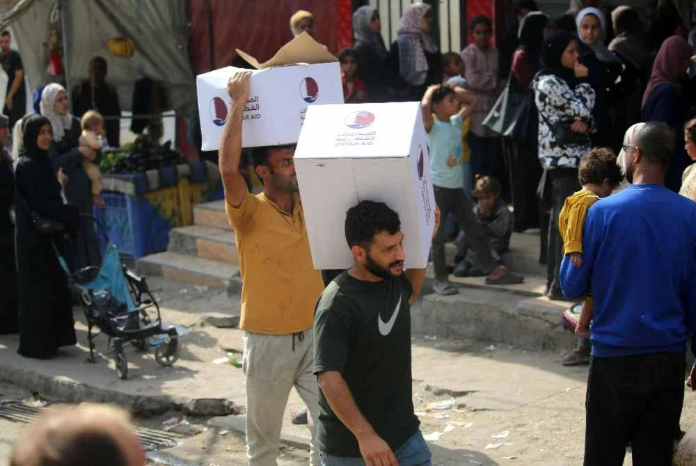 Penduduk Palestin membawa kotak makanan masing-masing, yang diambil di pusat pengagihan di kem pelarian Nuseirat di tengah Semenanjung Gaza. Foto AFP