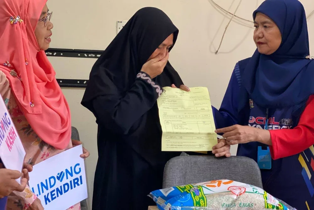 Hasliza (tengah) tidak dapat menahan sebak apabila menerima sumbangan FPM dan pencen penakat PERKESO yang diserahkan oleh Nora (kanan) di rumahnya Kampung Nibong Lemal, Pasir Mas pada Ahad. Foto: SINAR HARIAN/HAZELEN LIANA KAMARUDIN