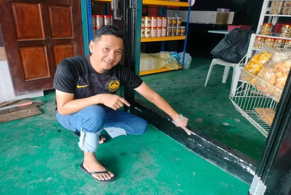 Zulkifli menunjukkan paras air pasang besar di kedainya pada Jumaat lalu.