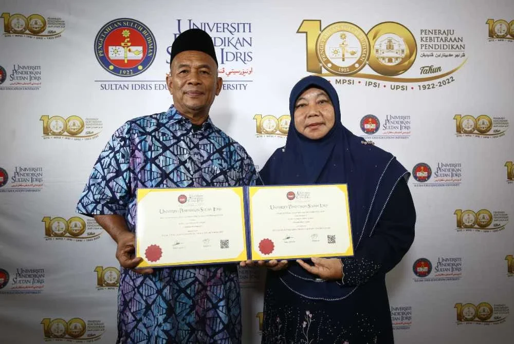 Azman (kiri) dan Kamariah menunjukkan ijazah yang diterima secara anumerta.