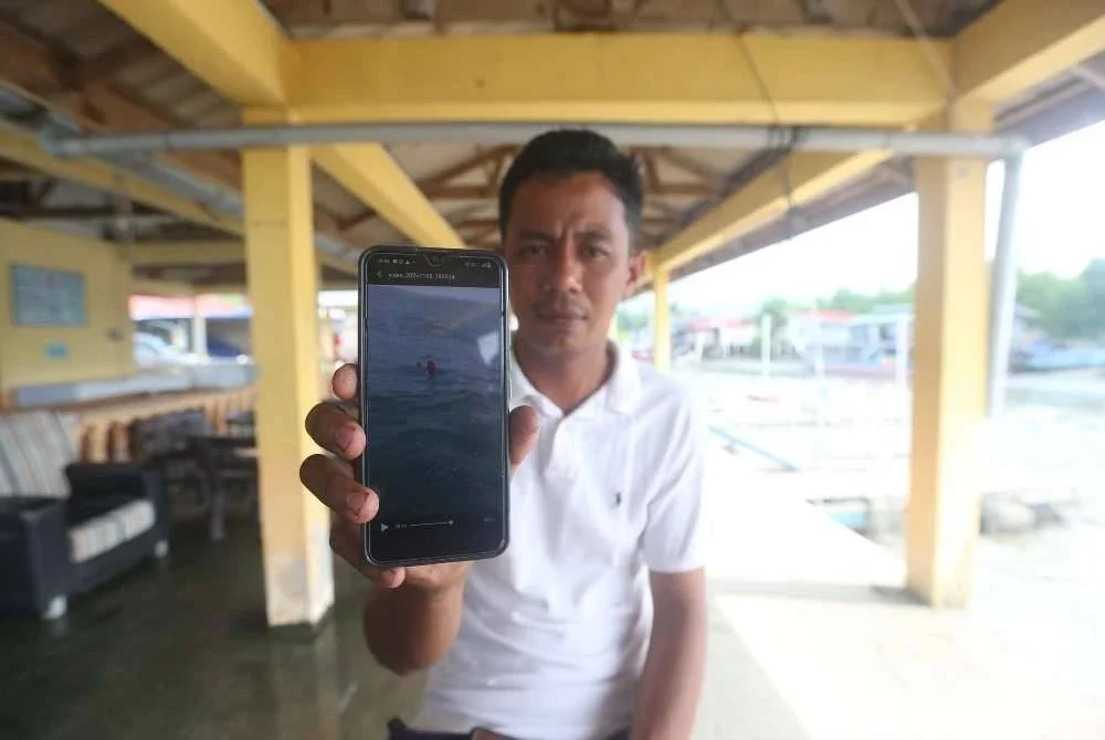 Muhd Azham menunjukkan gambr wanita yang diselamatkannya pada Sabtu lalu. 