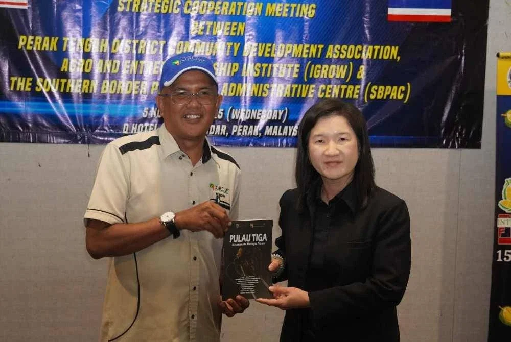 Nordin menyampaikan senaskhah buku Pulau Tiga kepada Kanokrat dalam kunjungan delegasi Thailand sempena Festival Durian Antarabangsa Kampung Gajah 2025 baru-baru ini.