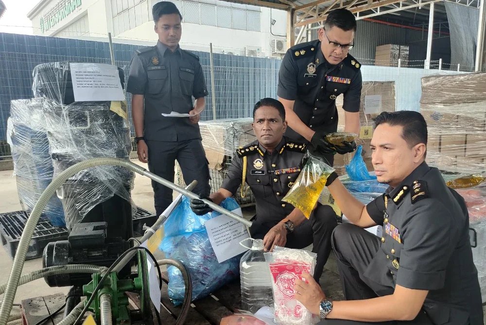 Jegan (dua dari kiri) menunjukkan minyak masak dan peralatan dirampas dalam Ops Tiris 3.0 pada sidang akhbar di Kompleks Penyimpanan KPDN, di Bukit Minyak pada Rabu.