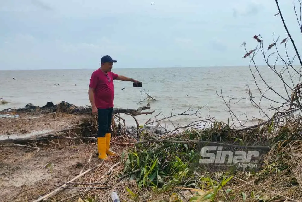 Khairul Azman menunjukkan tanah miliknya yang kian ‘hilang’, kesan hakisan pantai di Lorong Sayong, Kampung Rimba Terjun, Pontian.