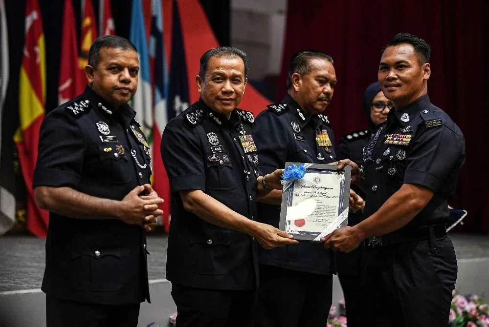 Mohd Khalid (dua, kiri) menyampaikan surat penghargaan kepada Sarjan Johnney Ambrose (kanan) pada Majlis Pengiktirafan Tolak Rasuah dan Sambutan Bulan Integriti Peringkat Polis Diraja Malaysia (PDRM) 2025 di Maktab PDRM, Cheras. - Foto Bernama 