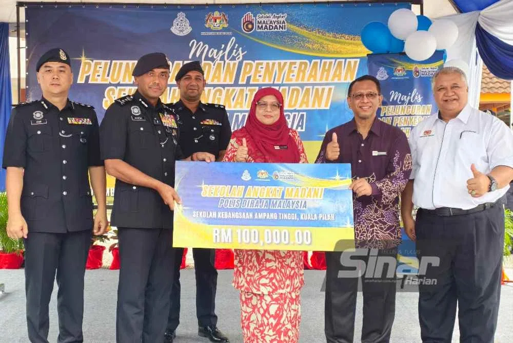 Alzafny menyerahkan sumbangan kepada pihak sekolah sambil diperhatikan Khalidah (tengah).