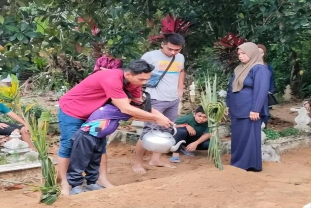 Muhammad Saiful bersama anaknya menyiram pusara isterinya yang meninggal dunia pada Rabu selepas tujuh tahun terlantar sakit di
Tanah Perkuburan Islam Permatang Pasir, Bachok.