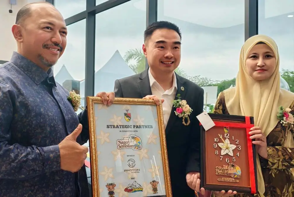 Mohd Zafir( kiri) dan Isnizawati (kanan) menyerahkan cenderahati kepada Ryan.