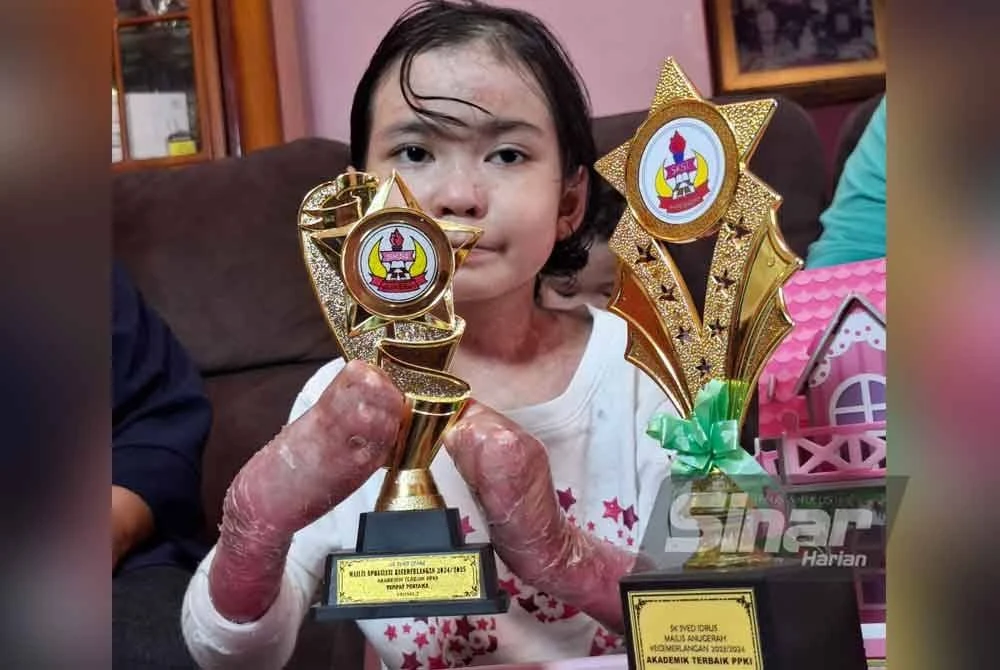 Aina Afieyah menunjukkan piala yang diperolehi hasil kecemerlangan dalam akademik di SK Syed Idrus.