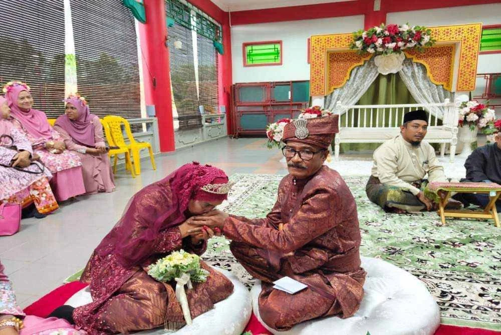 Mahriah bersalam tangan suaminya semasa upacara menyarung cincin dijalankan.