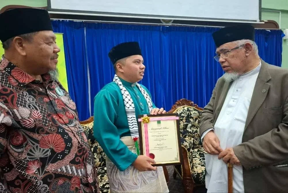 Muhammad Azmi (kanan) bersama penerima Tokoh Sukarelawan Ummah Negeri Perak 2025, Muhammad Aqil Danish Razlan, 24, (tengah) sempena Majlis Perhimpunan Sukarelawan Penggerak Ummah dan Humaniti Negeri Perak di Institut Tadbiran Islam Perak (INTIM) di Ipoh pada Sabtu.
