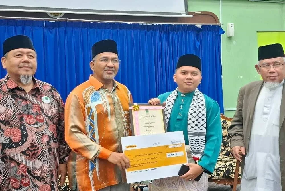 Graduan undang-undang Universiti Islam Antarabangsa Malaysia, Muhammad Aqil Danish Razlan (dua dari kanan) menerima Tokoh Sukarelawan Ummah Negeri Perak 2025 yang disampaikan Saiful Azizi sambil diperhatikan Muhammad Azmi (kanan).
