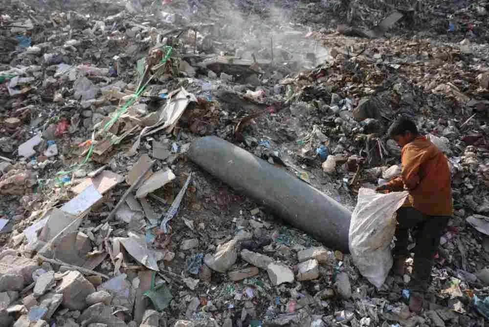 Seorang kanak-kanak lelaki Palestin mengutip plastik berhampiran sebuah peluru yang tidak meletup di kawasan pembuangan sampah di pasar Firas, Bandar Gaza. Foto AFP