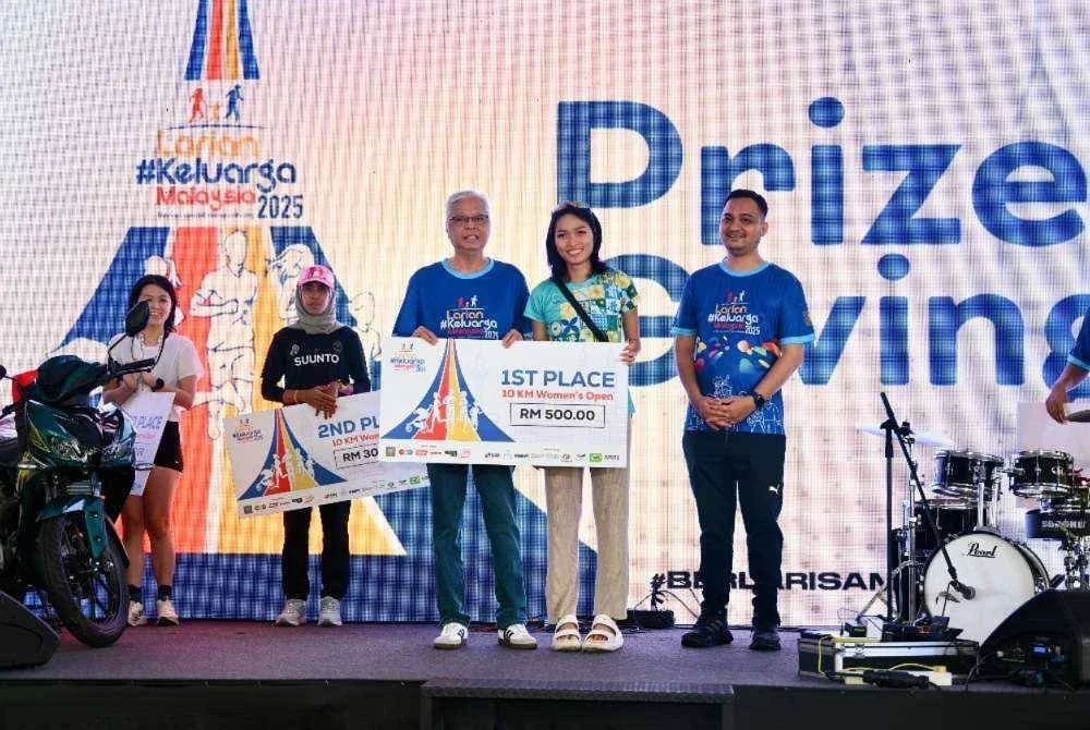 Ismail Sabri (kiri) menyampaikan medal dan replika cek kepada johan 10km kategori wanita.