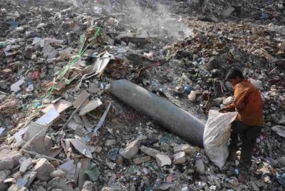 Seorang kanak-kanak lelaki Palestin mengutip plastik berhampiran sebuah peluru yang tidak meletup di kawasan pembuangan sampah di pasar Firas, Bandar Gaza. Foto AFP
