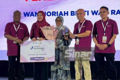 Wan Noriah (tengah) menerima anugerah yang disampaikan oleh Mohd Shahrim (dua dari kanan).
