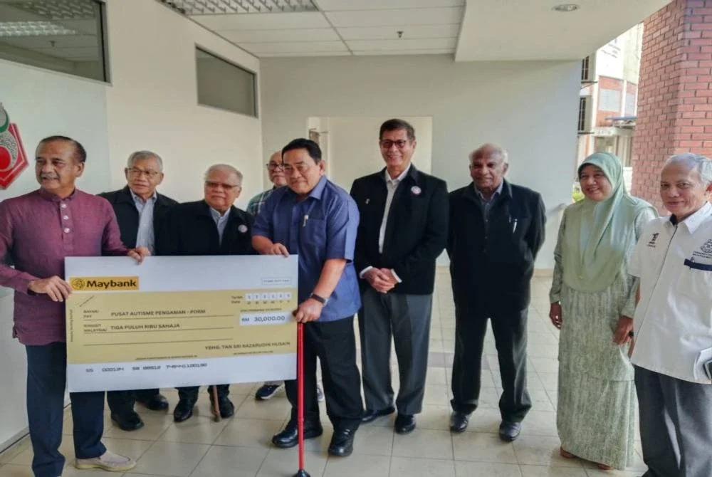 Razarudin (kiri) menyerahkan sumbangan kepada Persatuan Autisme PDRM di PULAPOL, Kuala Lumpur pada Isnin. 